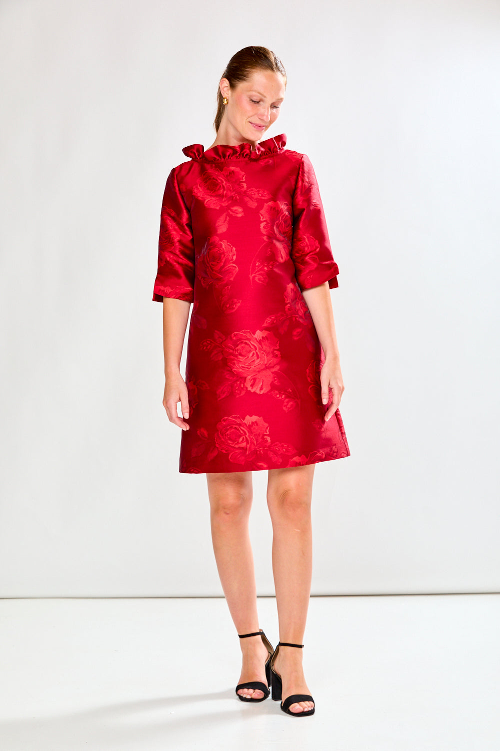 Woman wearing a red dress with floral pattern on a white background