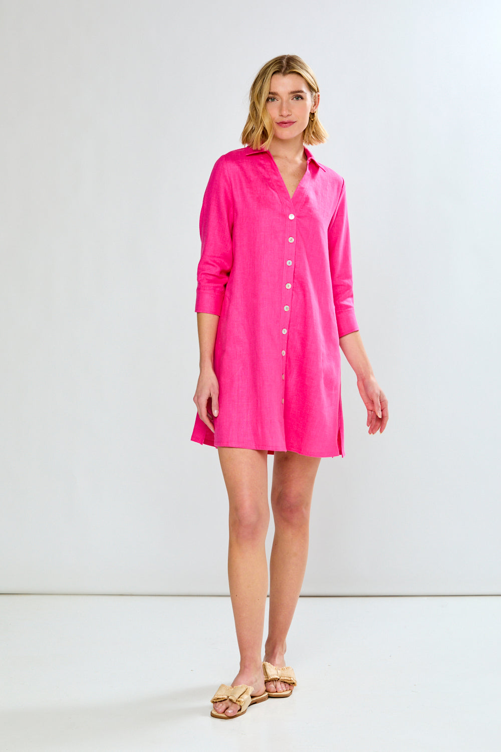 Woman wearing a bright pink shirt dress against a white background