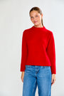 Woman wearing a red sweater and blue jeans on a white background