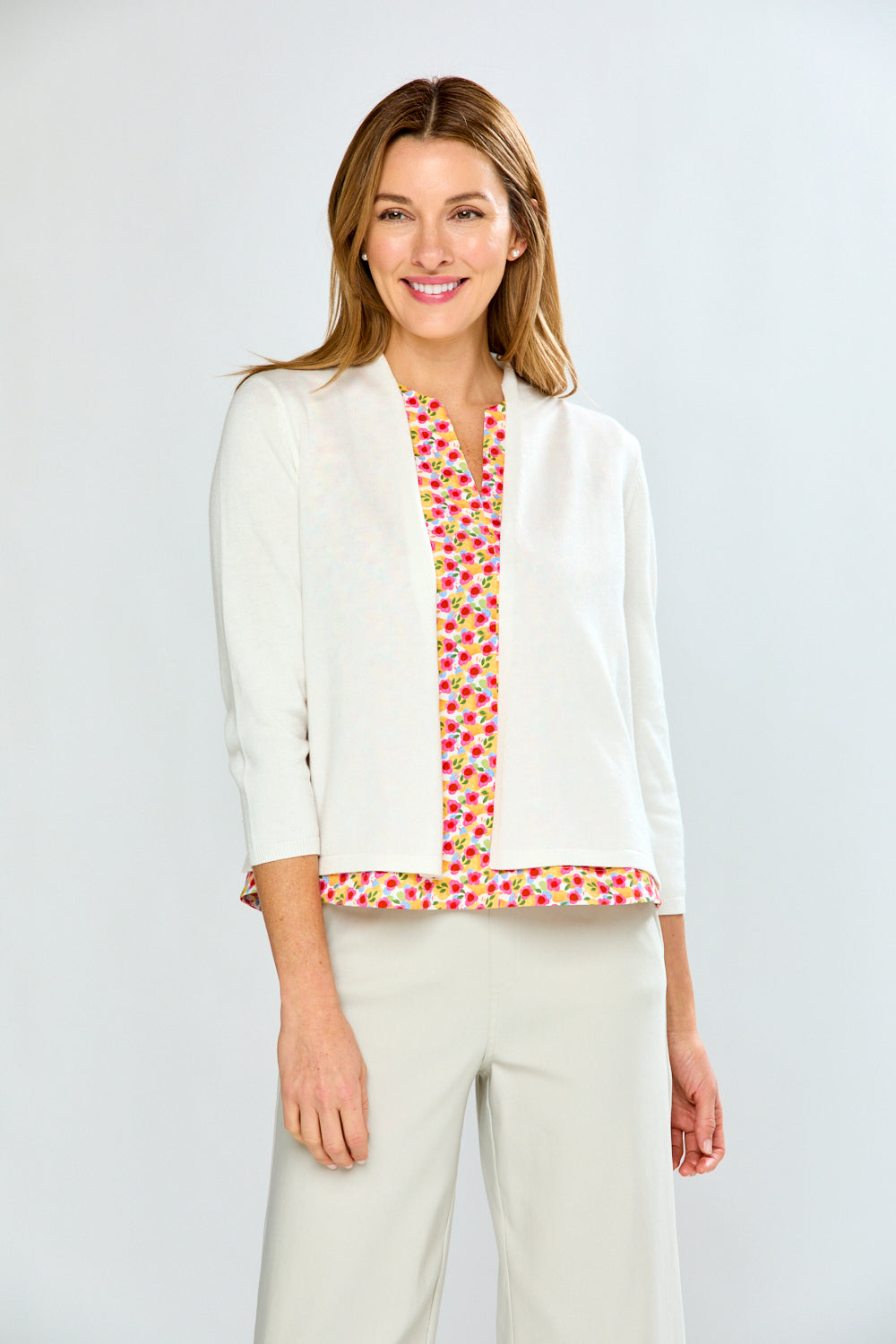 Woman wearing a white blouse with a colorful patterned trim on a plain background