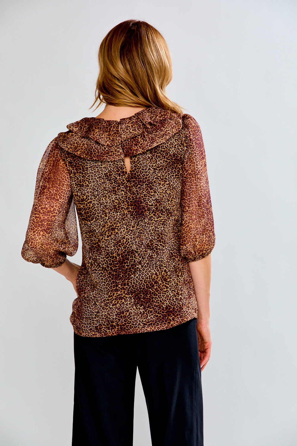 Woman wearing a brown patterned blouse with a hood against a white background