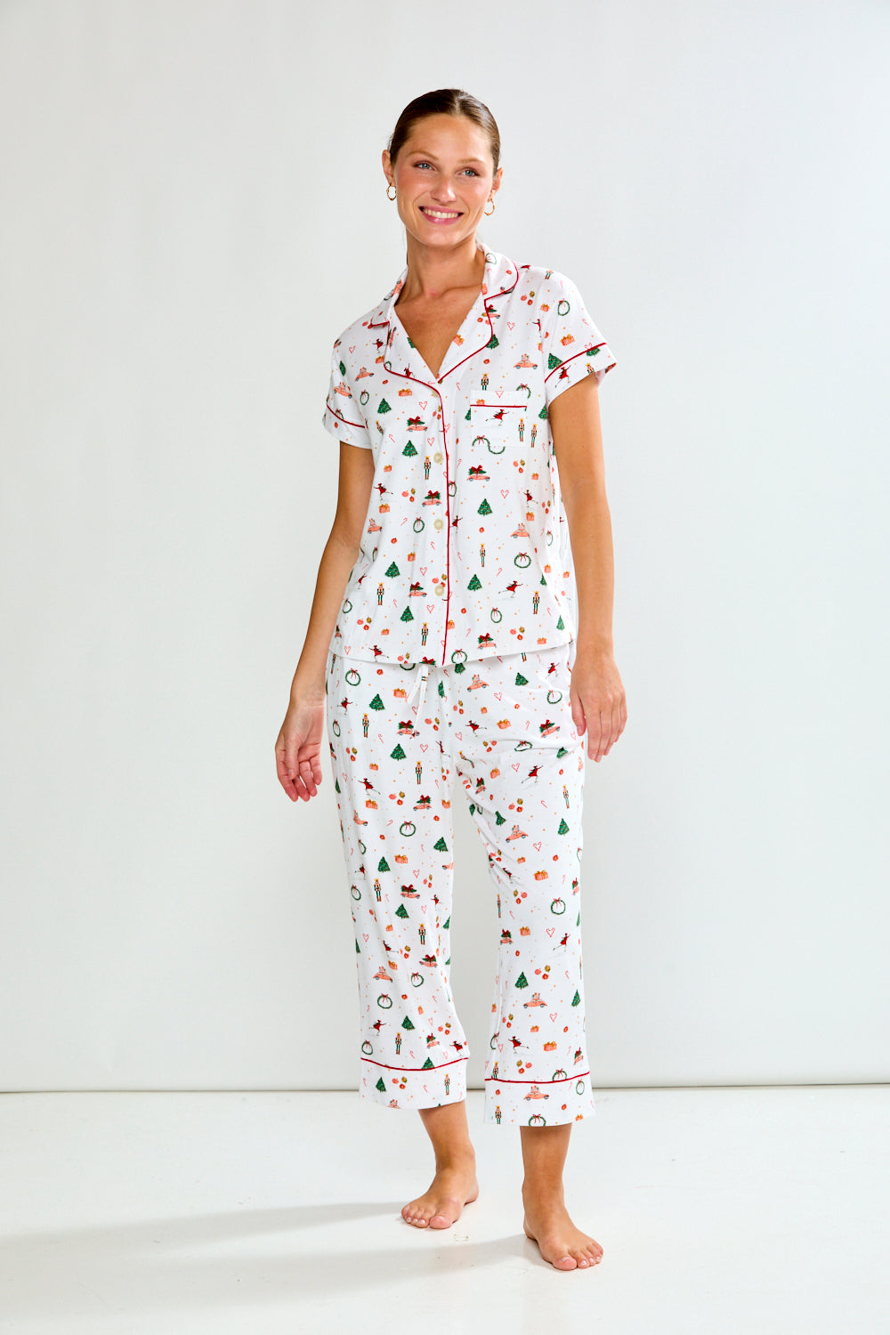 Woman wearing a white pajama set with colorful patterns on a white background