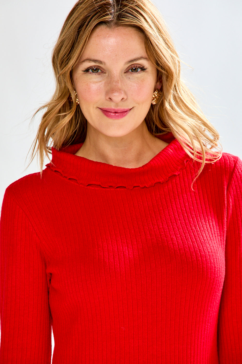 Woman wearing a red sweater and plaid pants on a white background