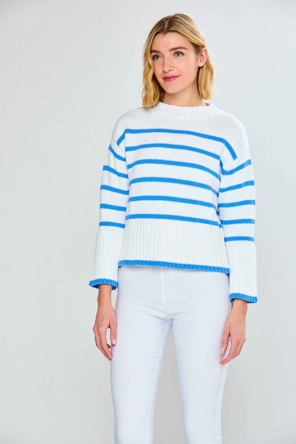 Woman wearing a white sweater with blue stripes against a plain background