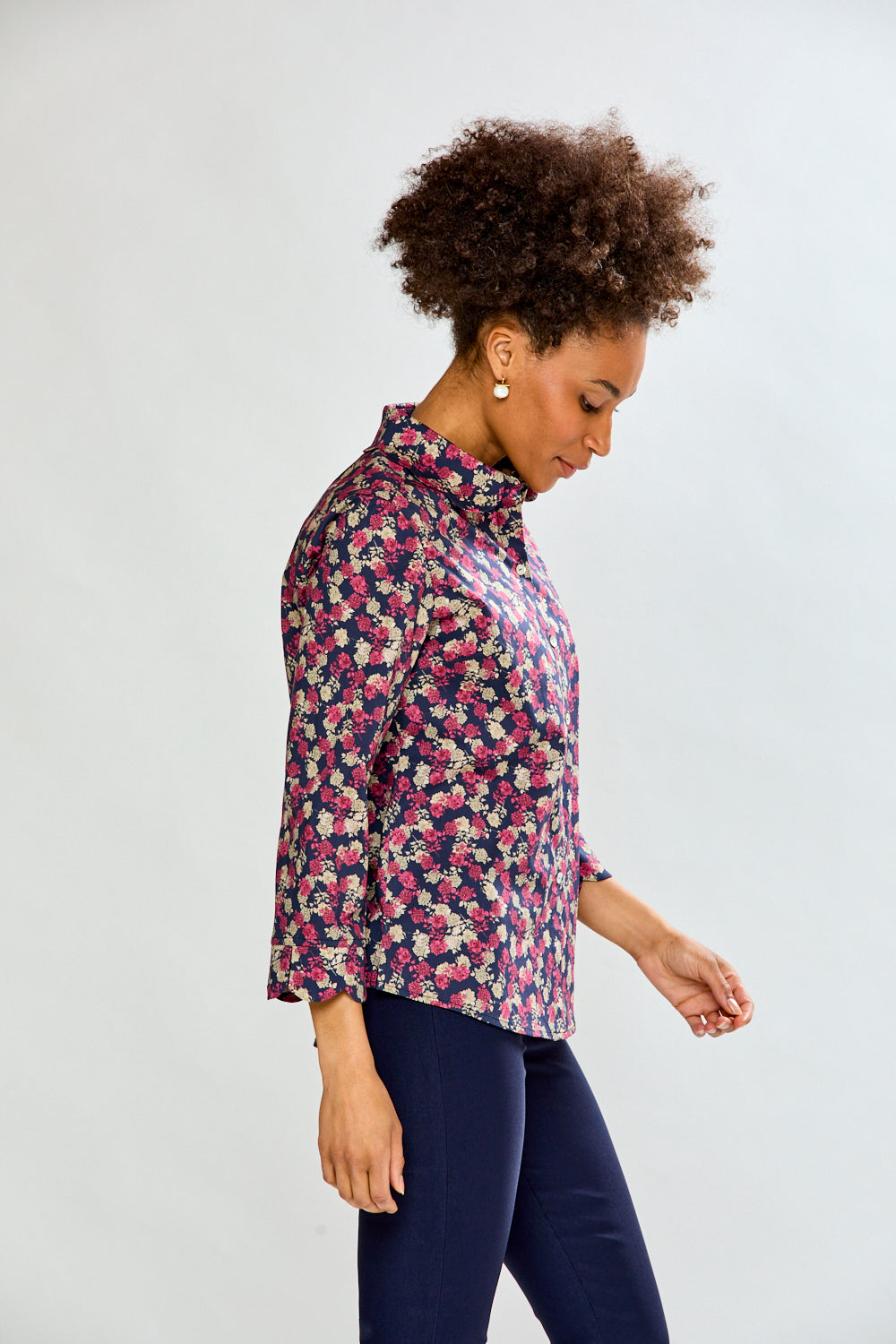 Woman wearing a floral shirt and dark pants on a white background