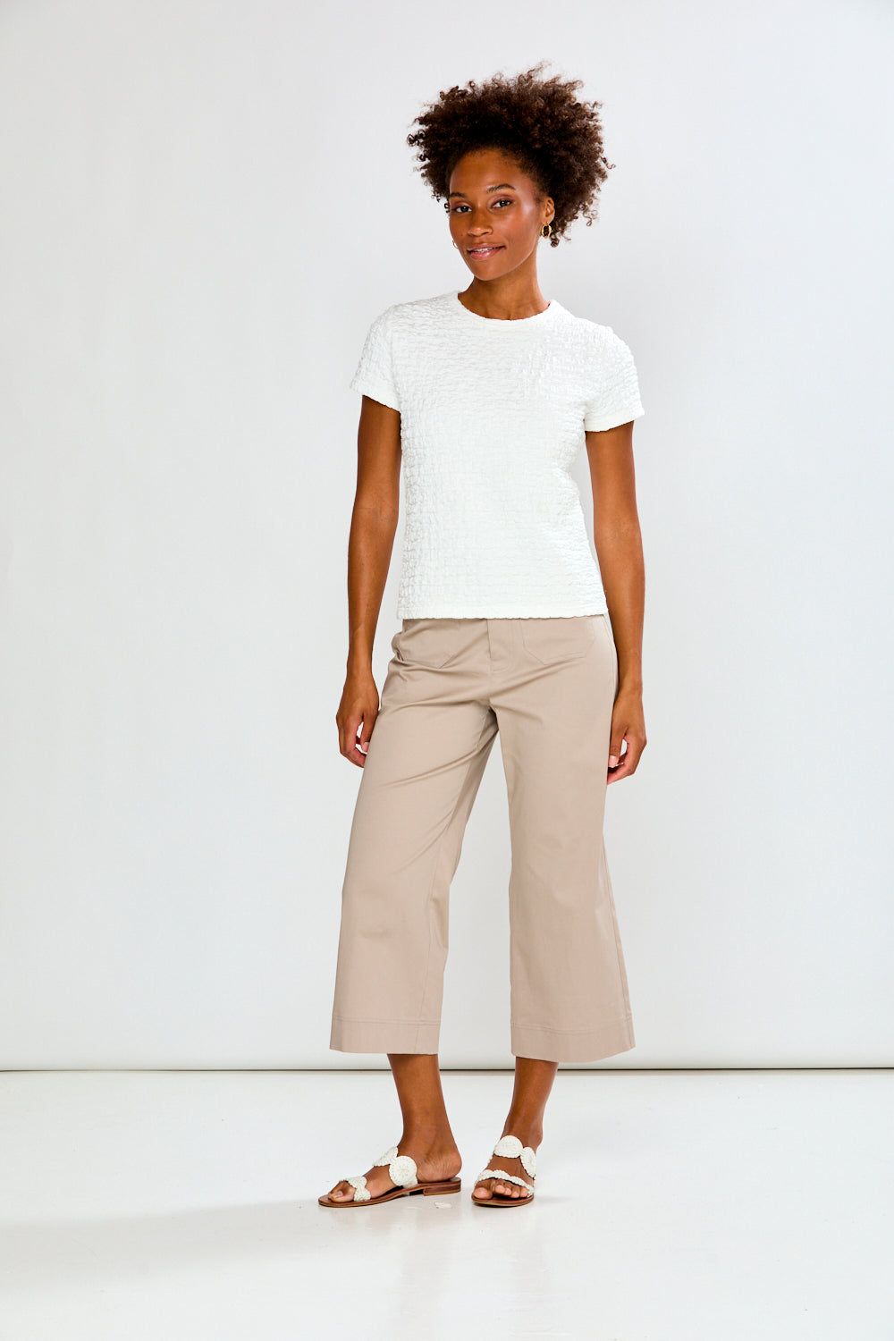 Woman wearing a white t-shirt and beige pants on a white background