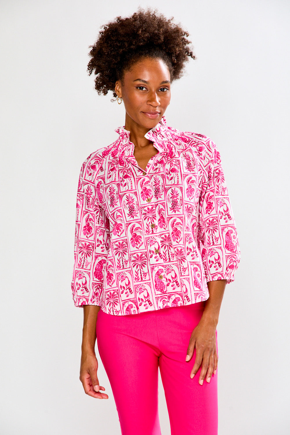 Woman wearing a pink patterned blouse and pink pants on a white background