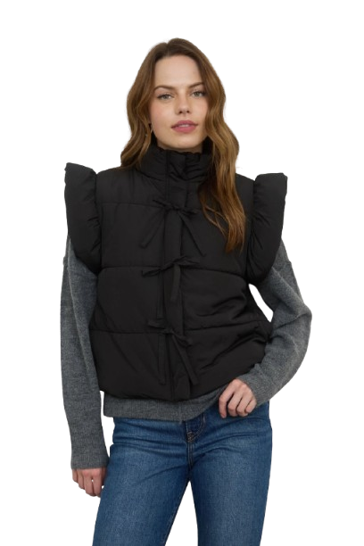 Woman wearing a black puffer vest over a gray sweater with a white background