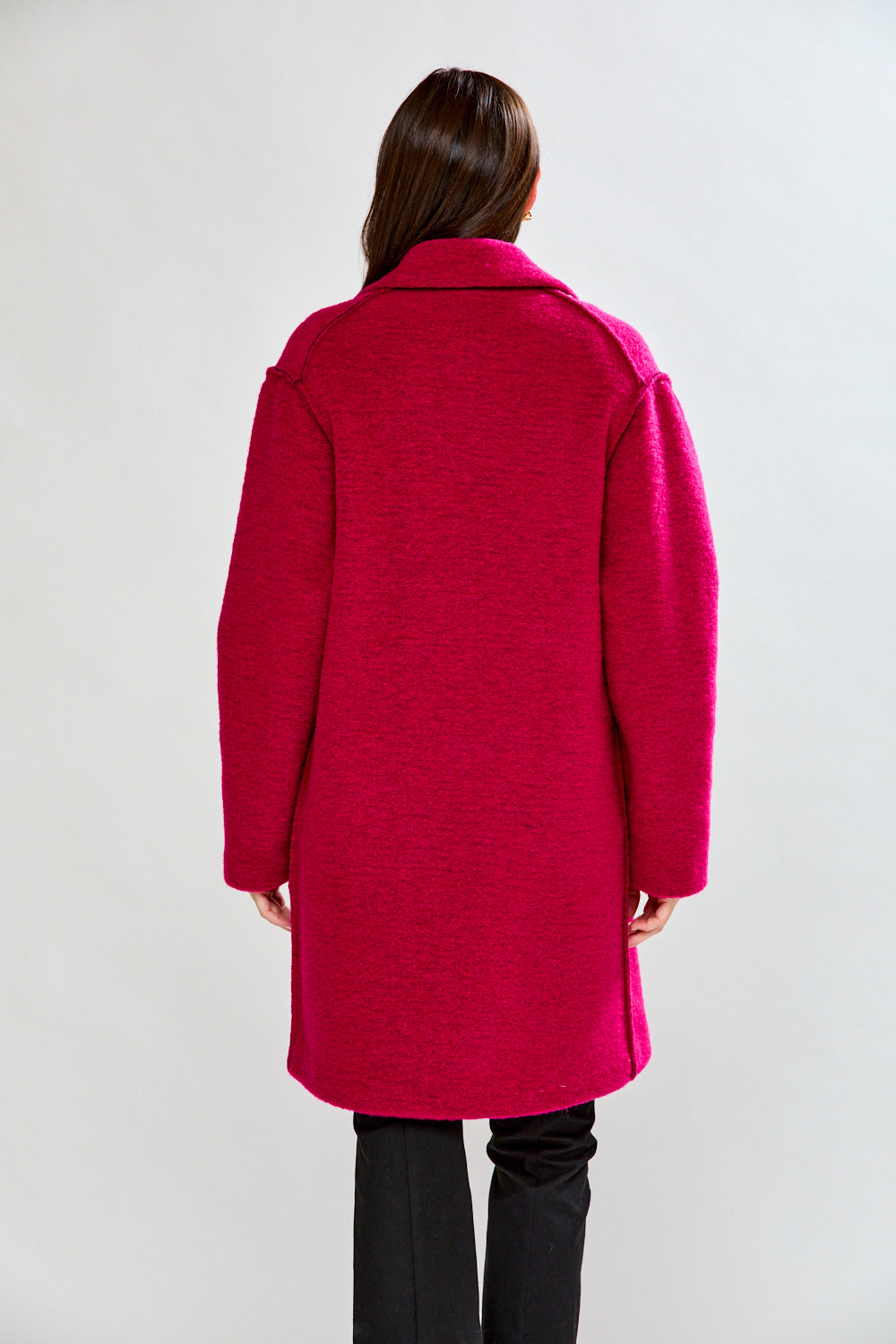 Woman wearing a bright pink coat against a white background