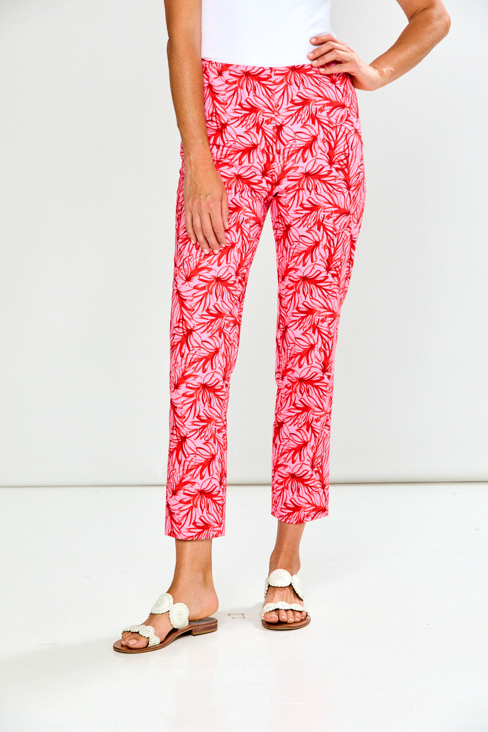 Person wearing pink leaf-patterned pants on a white background