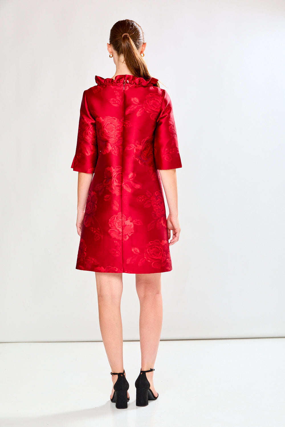 Woman wearing a red dress with floral pattern on a white background