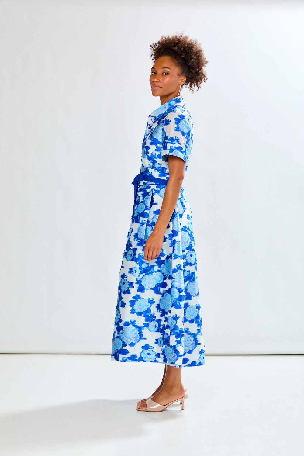 Woman wearing a blue floral dress against a white background