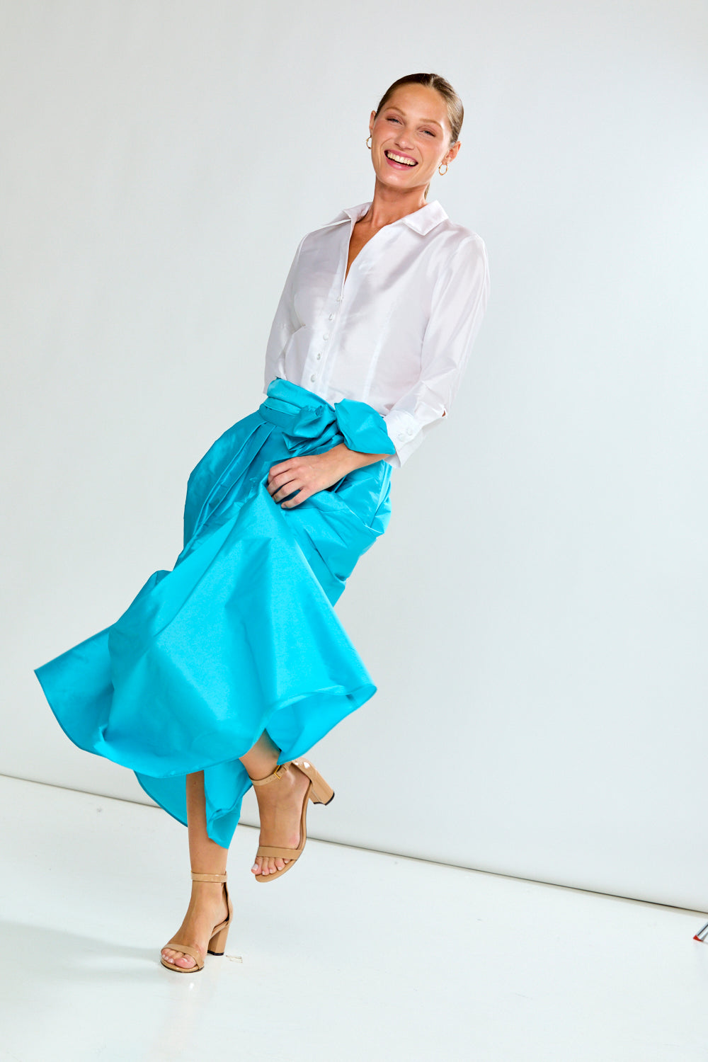 Woman wearing a white shirt and blue skirt on a white background