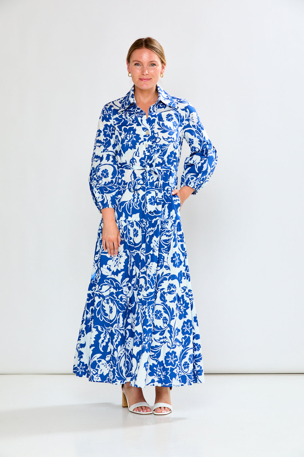 Woman wearing a blue and white floral dress against a white background