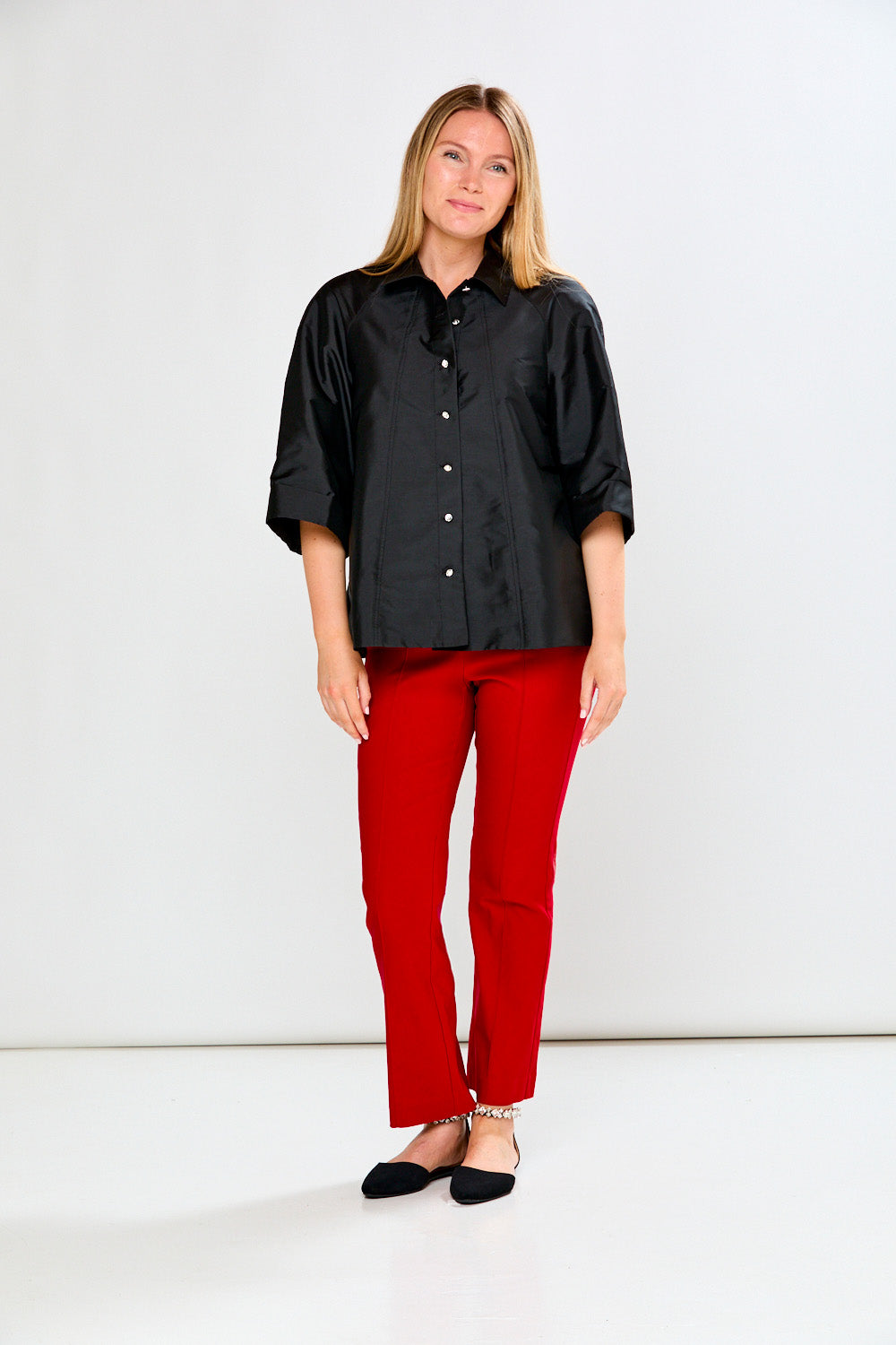Woman wearing a black shirt and red pants on a white background