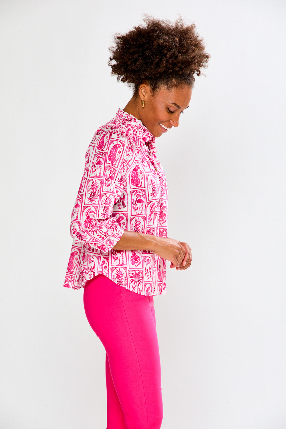 Woman wearing a pink patterned blouse and pink pants on a white background