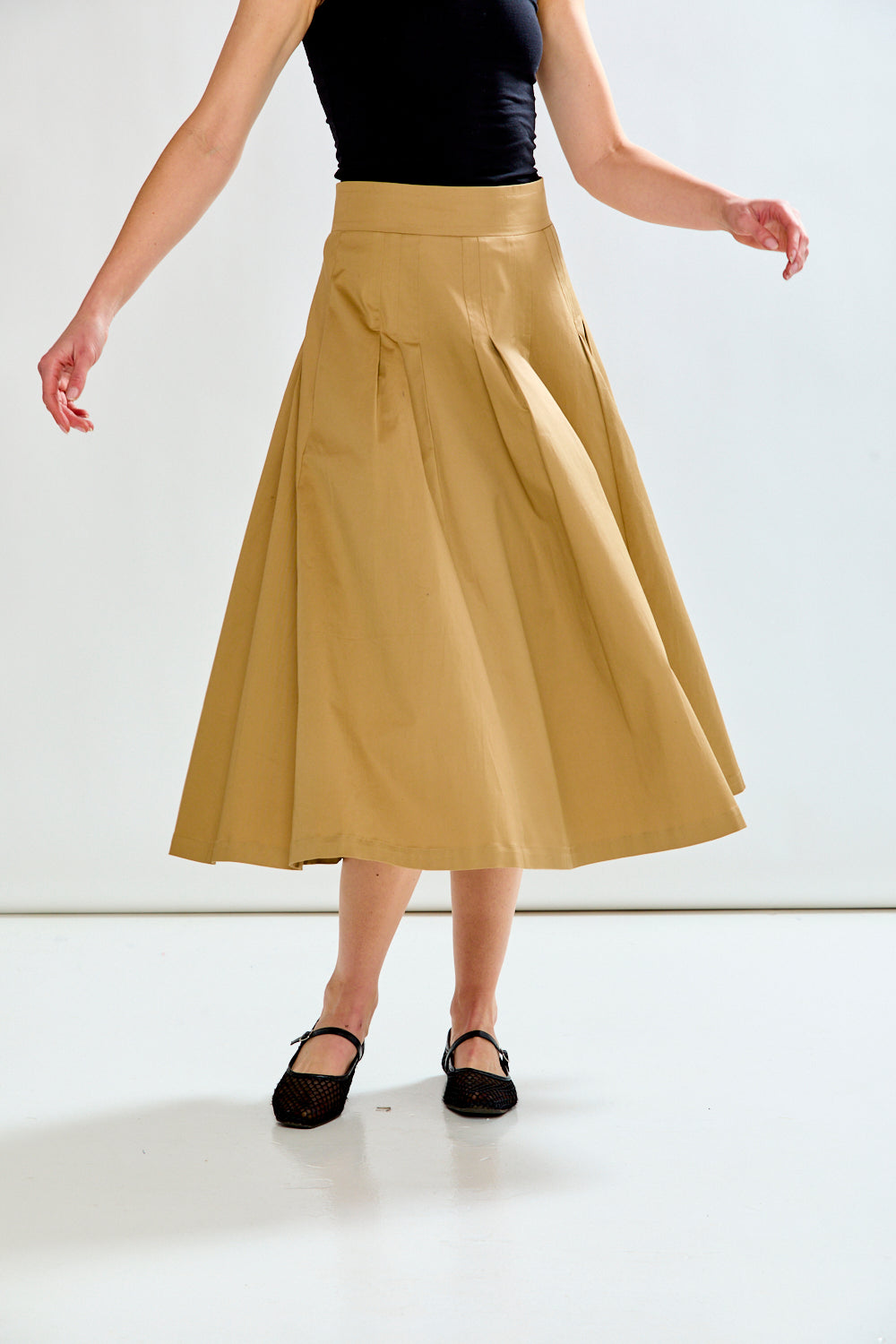 Woman wearing a black top and beige skirt on a white background