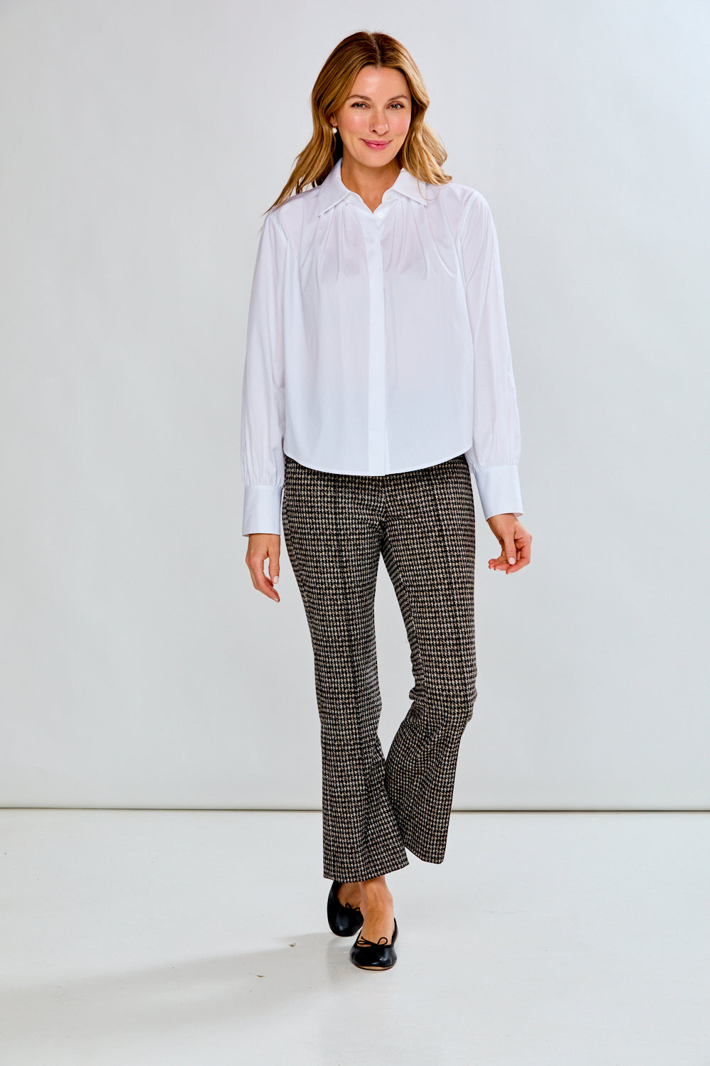 Person wearing houndstooth patterned pants on a plain background