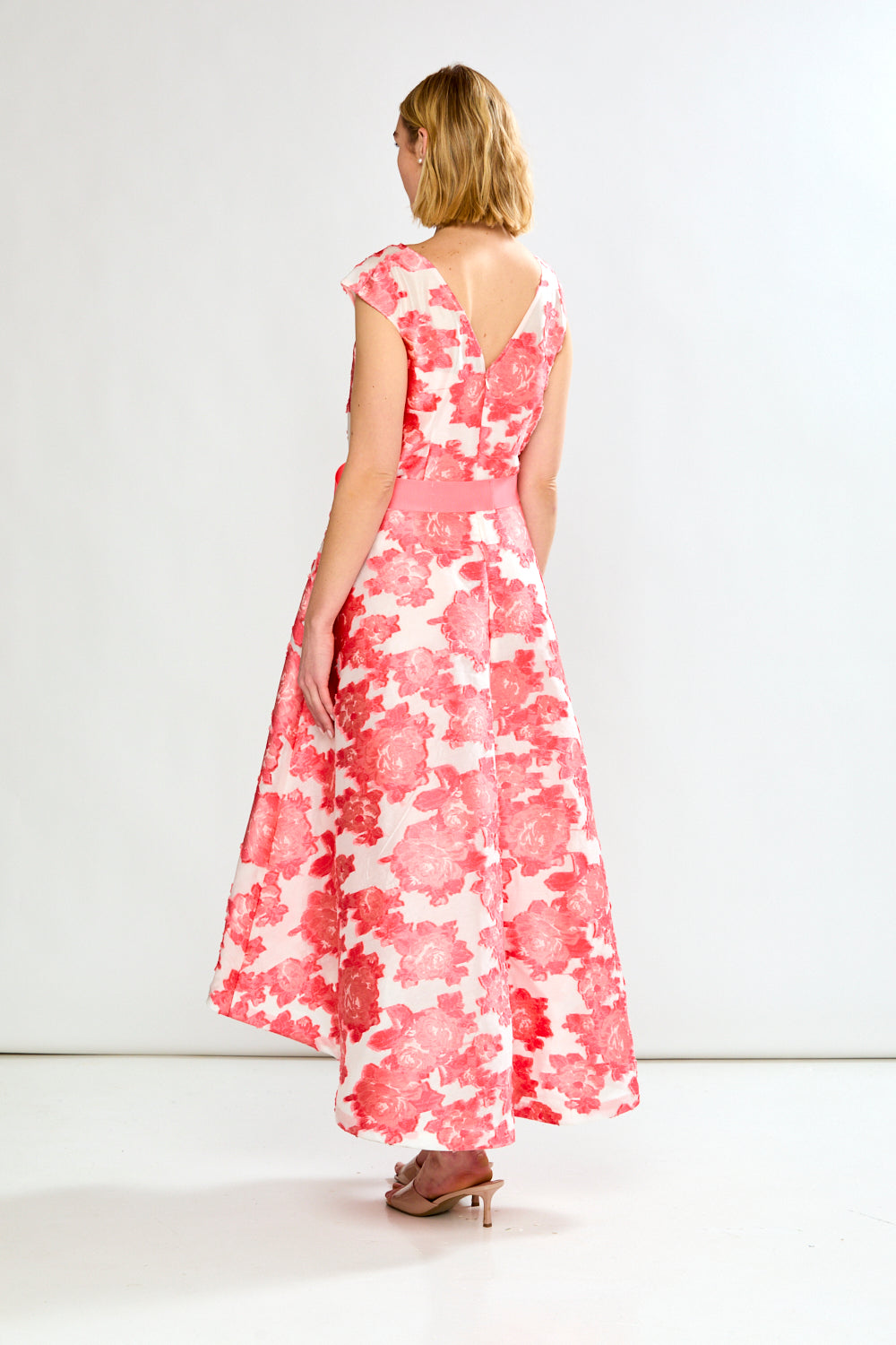 Woman wearing a pink and white floral dress on a white background