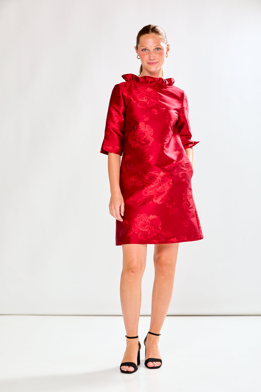 Woman wearing a red dress with floral pattern on a white background
