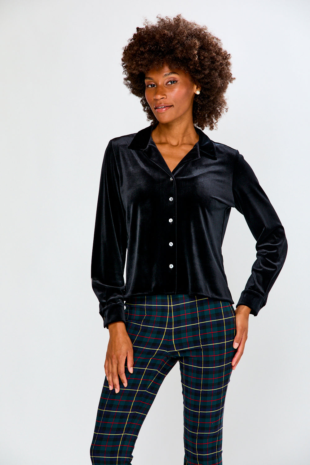 Woman wearing a black satin shirt and plaid pants on a white background