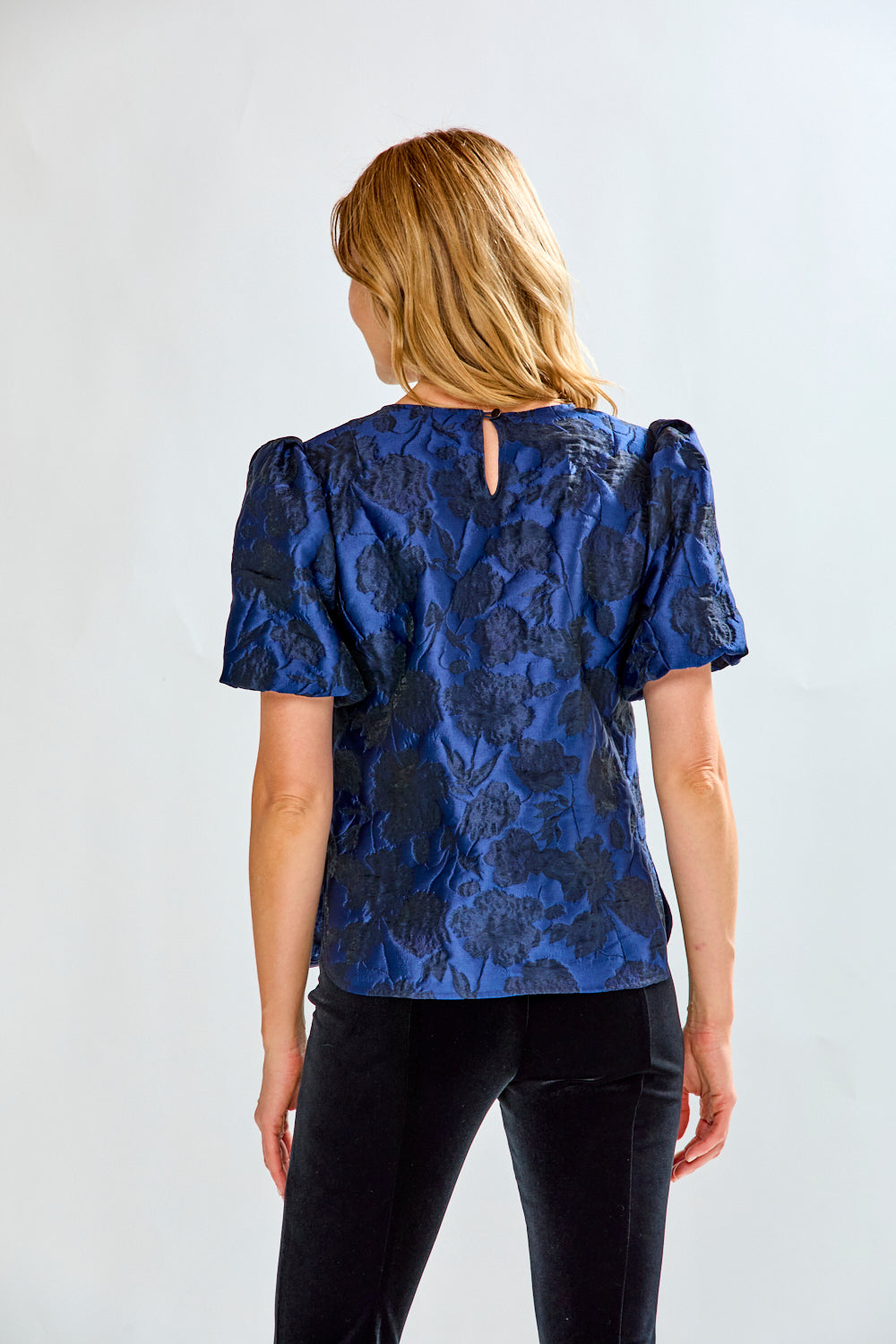 Woman wearing a blue floral blouse with puff sleeves against a white background