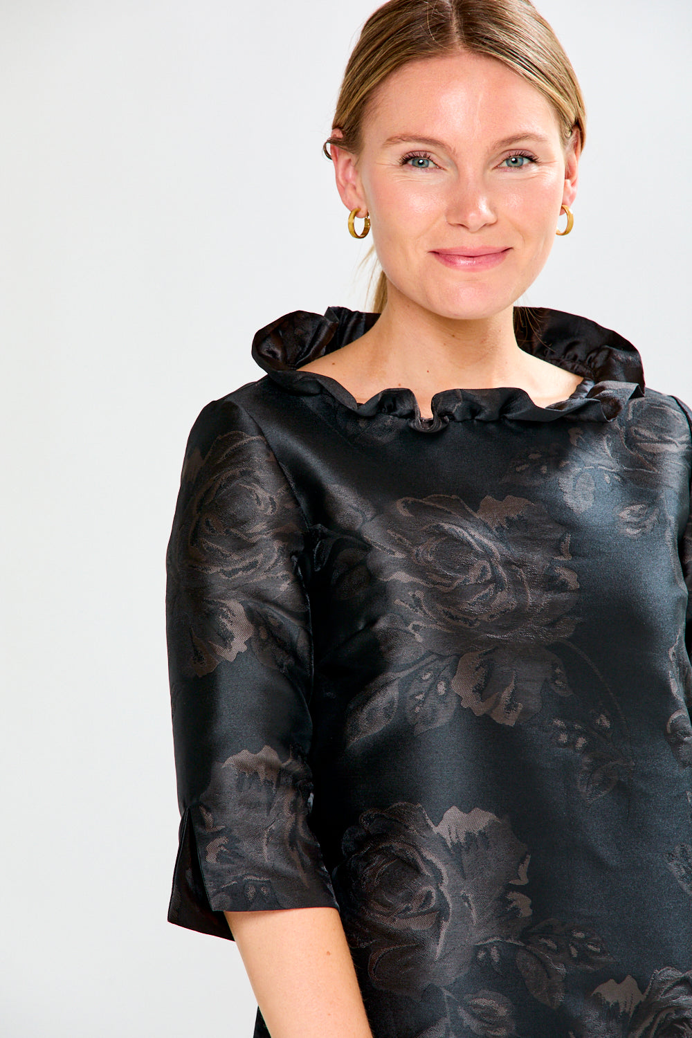 Woman wearing a black floral dress against a white background