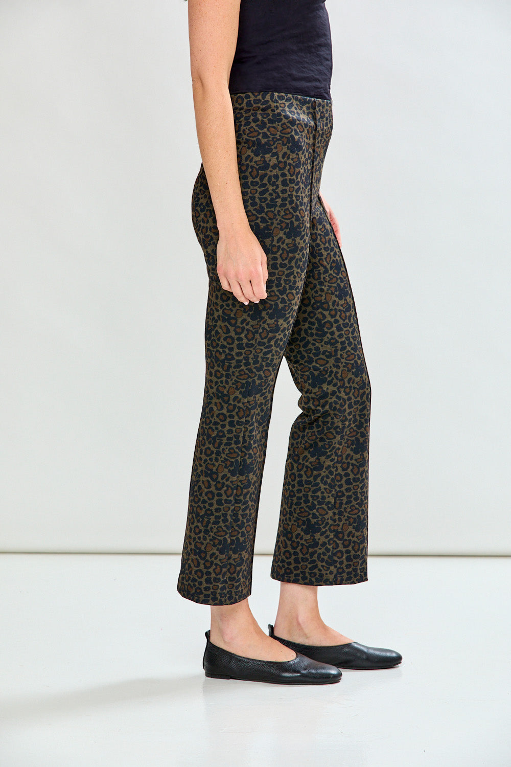 Woman wearing leopard print pants on a plain background