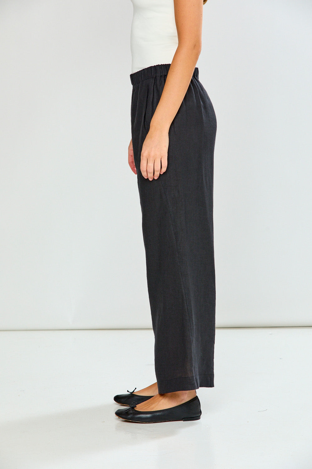 Person wearing black pants and a white top on a light background