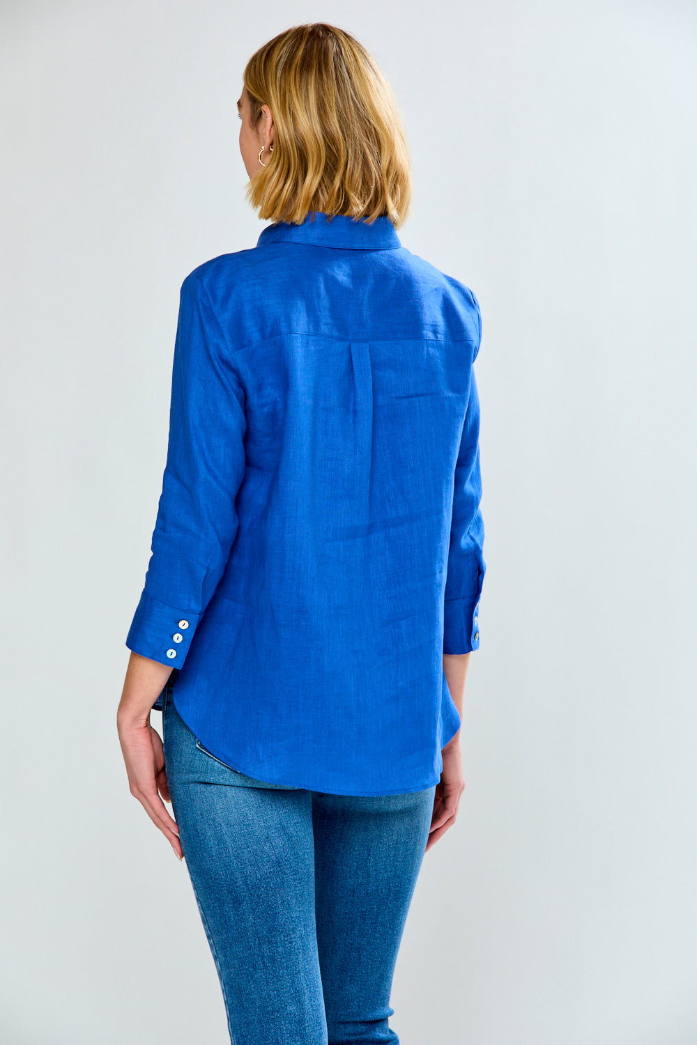 Person wearing a blue shirt and jeans on a plain background