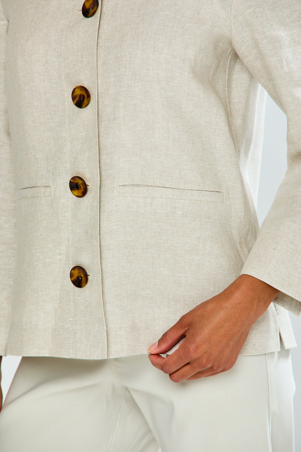 Close-up of a beige blazer with brown buttons on a white background