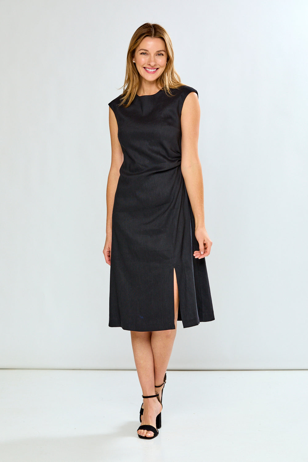 Woman wearing a black dress with a slit on a white background