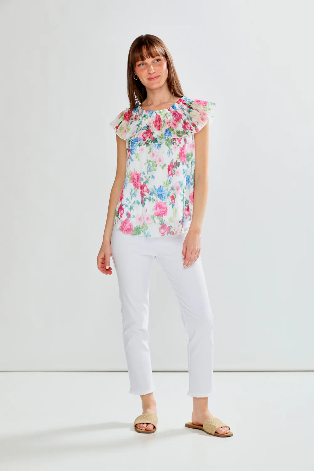 Woman wearing a floral blouse and white pants on a white background