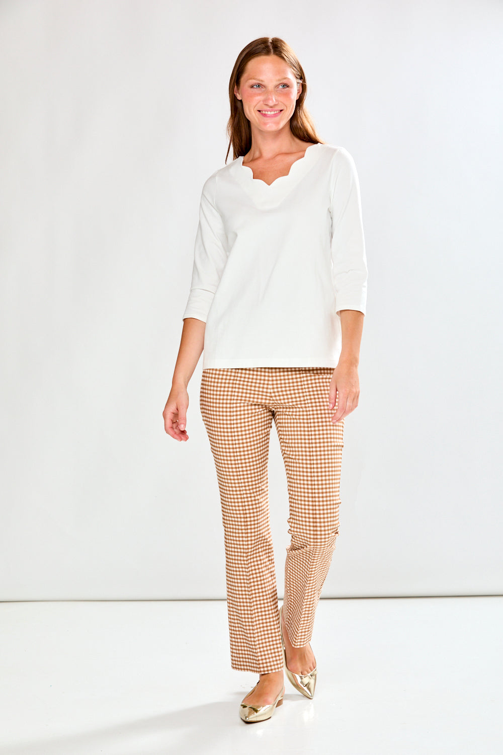 Woman wearing a white top and checkered pants on a white background