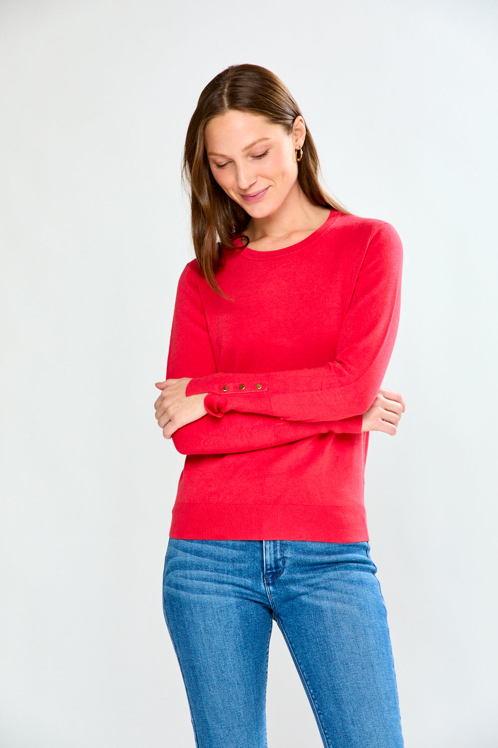Woman wearing a pink sweater and light blue jeans on a white background