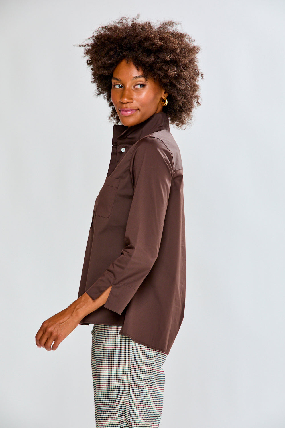 Woman wearing a chocolate shirt and plaid pants on a white background