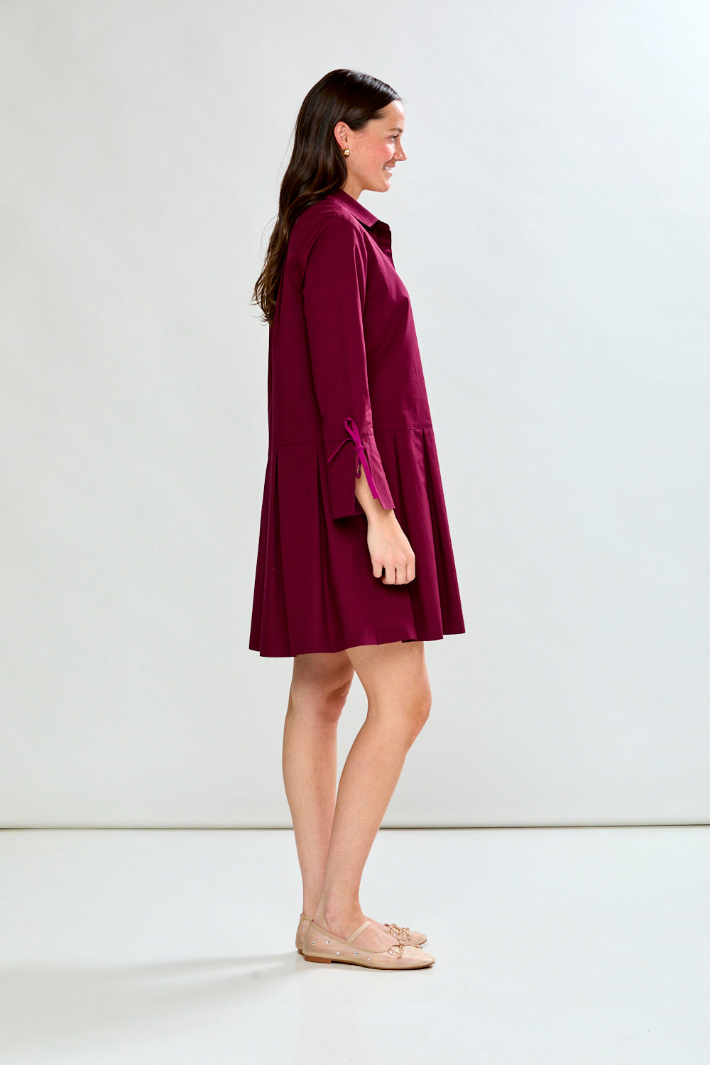Woman wearing a raisin dress with long sleeves on a white background