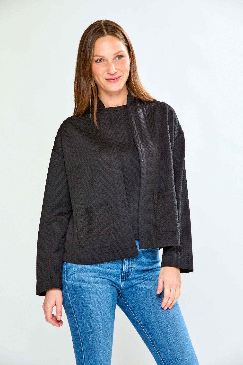 Woman wearing a black jacket and blue jeans on a white background