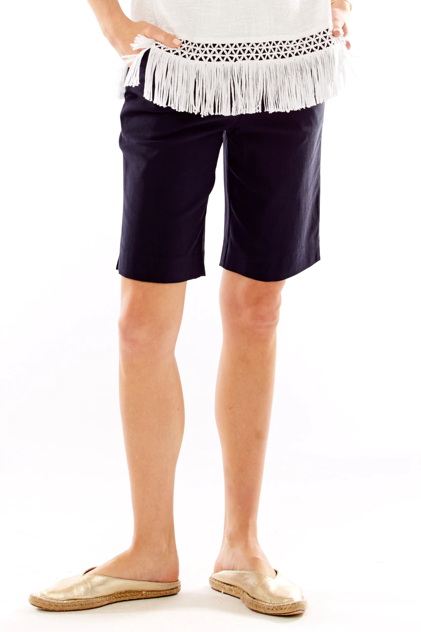 Person wearing navy shorts with a white top and fringe detail on a white background
