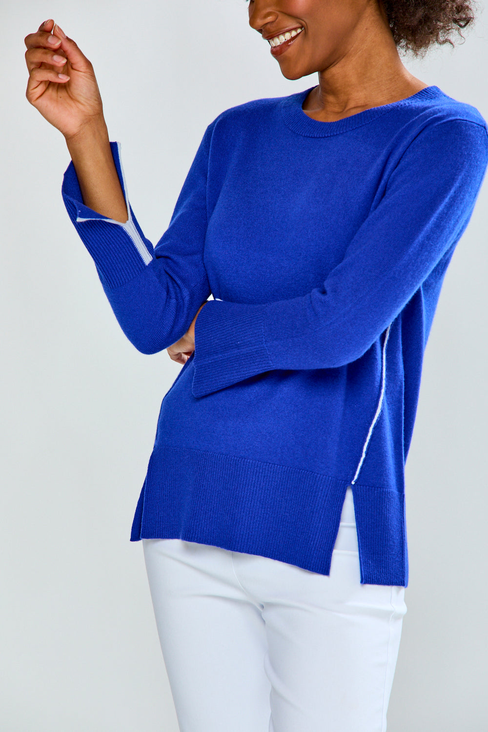 Person wearing a blue sweater with white trim on a plain background