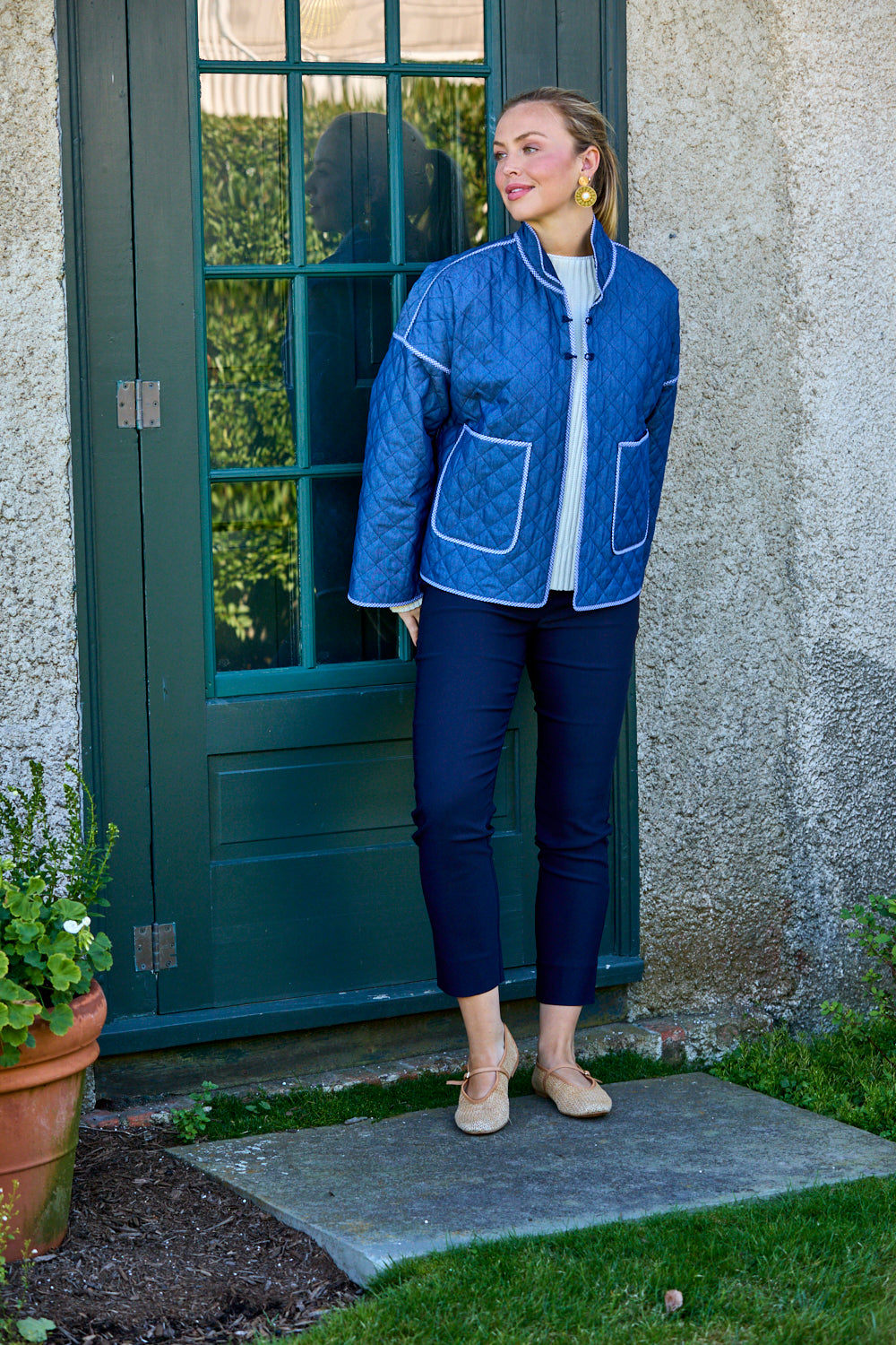 Woman wearing a blue quilted jacket standing outside a building.