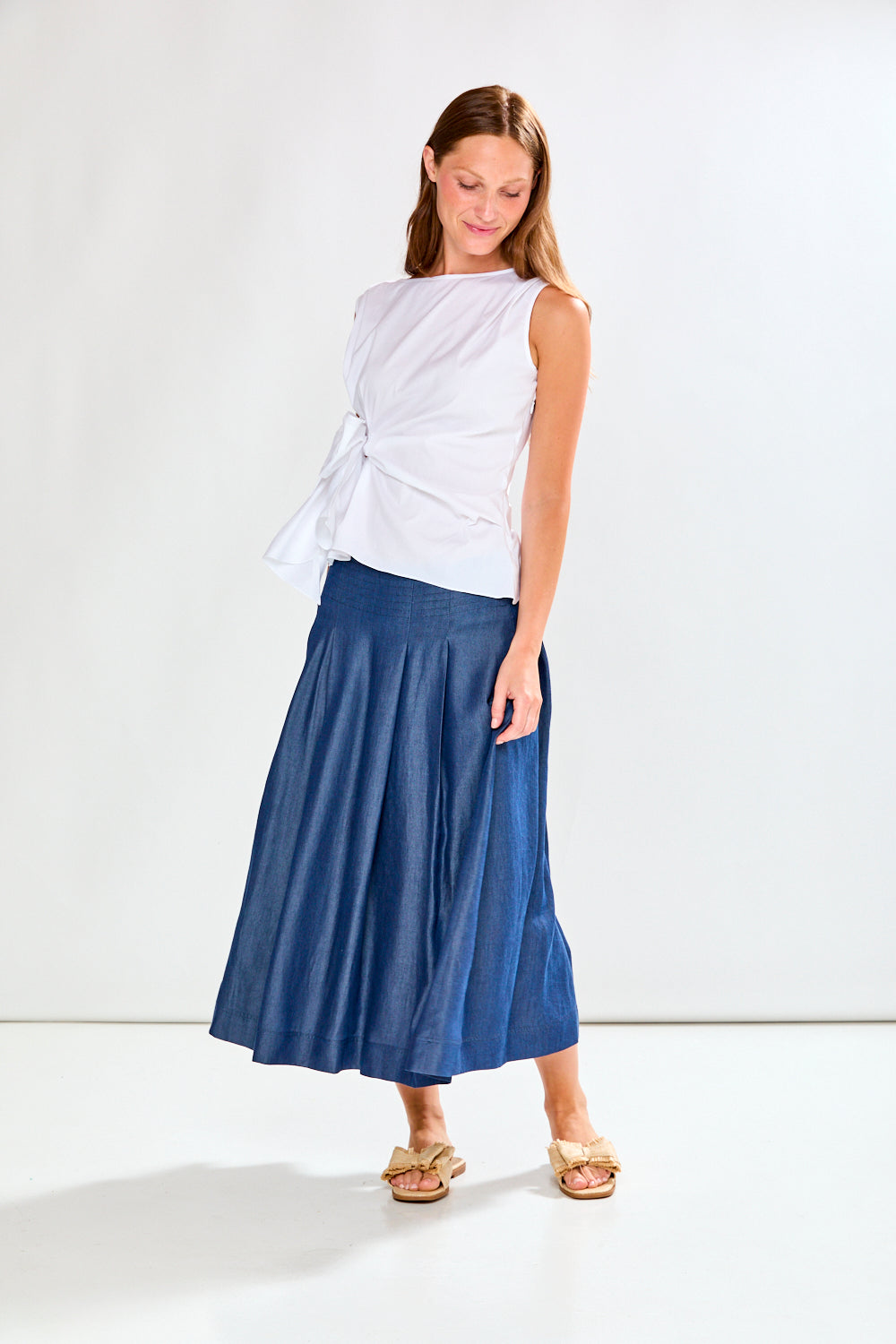 Woman wearing a white top and blue skirt on a white background
