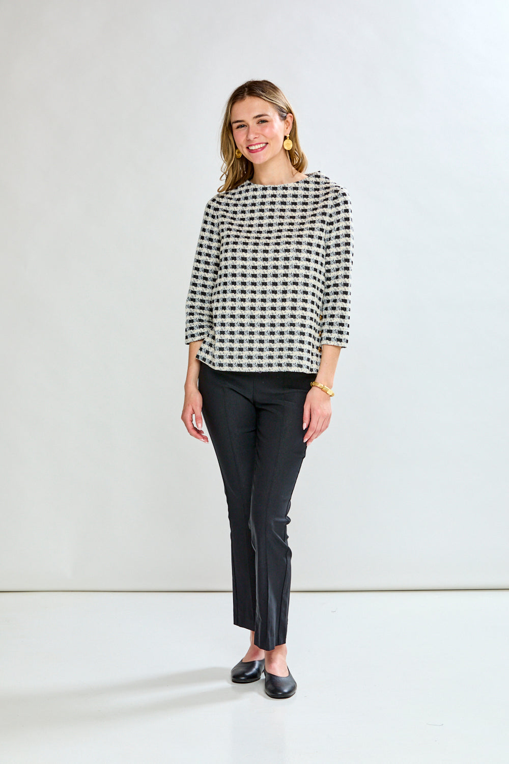 Woman wearing a black and white checkered blouse against a plain background