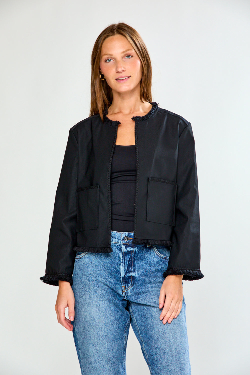 Woman wearing a black jacket and blue jeans on a white background