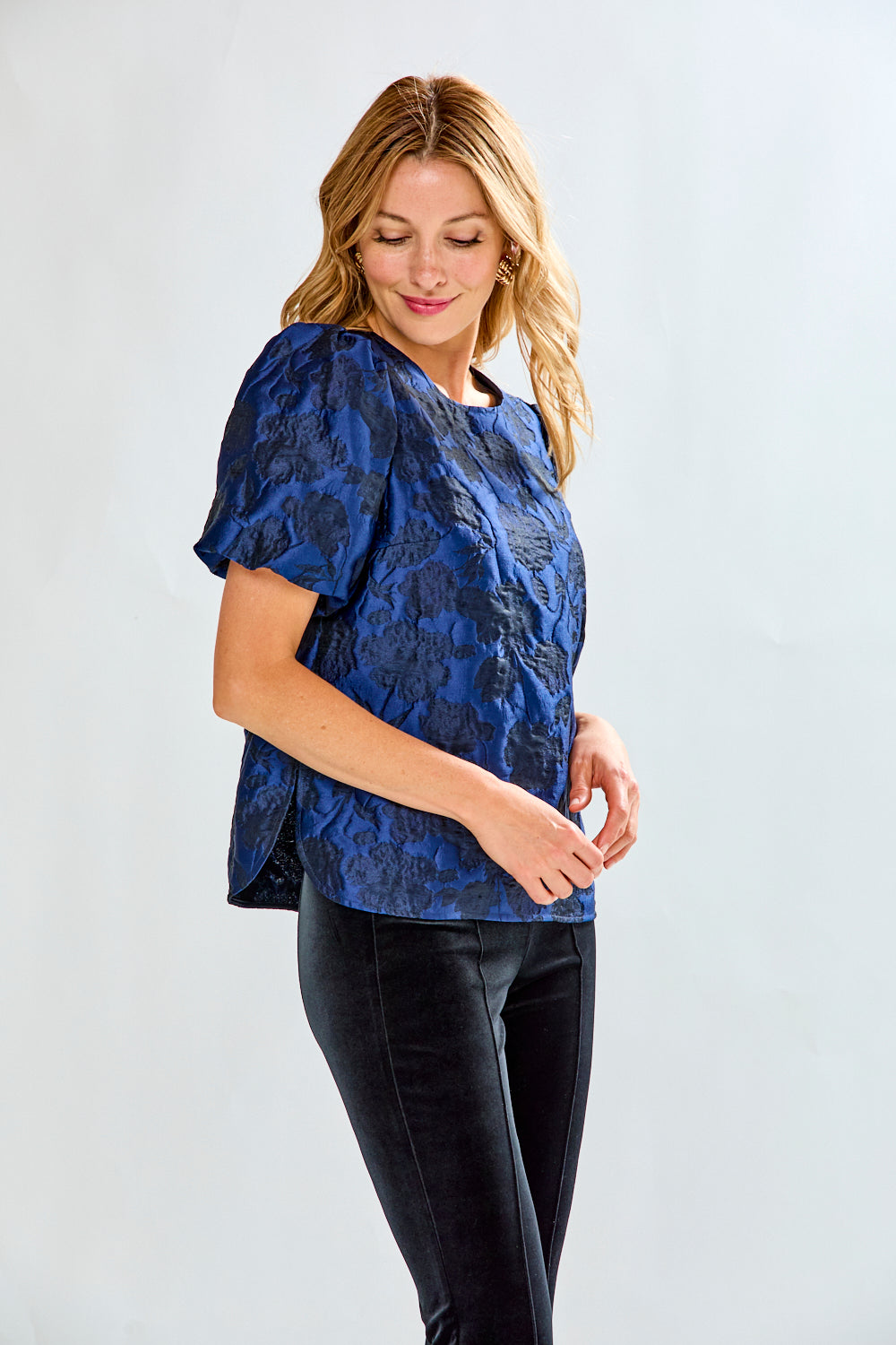Woman wearing a blue floral blouse with puff sleeves against a white background