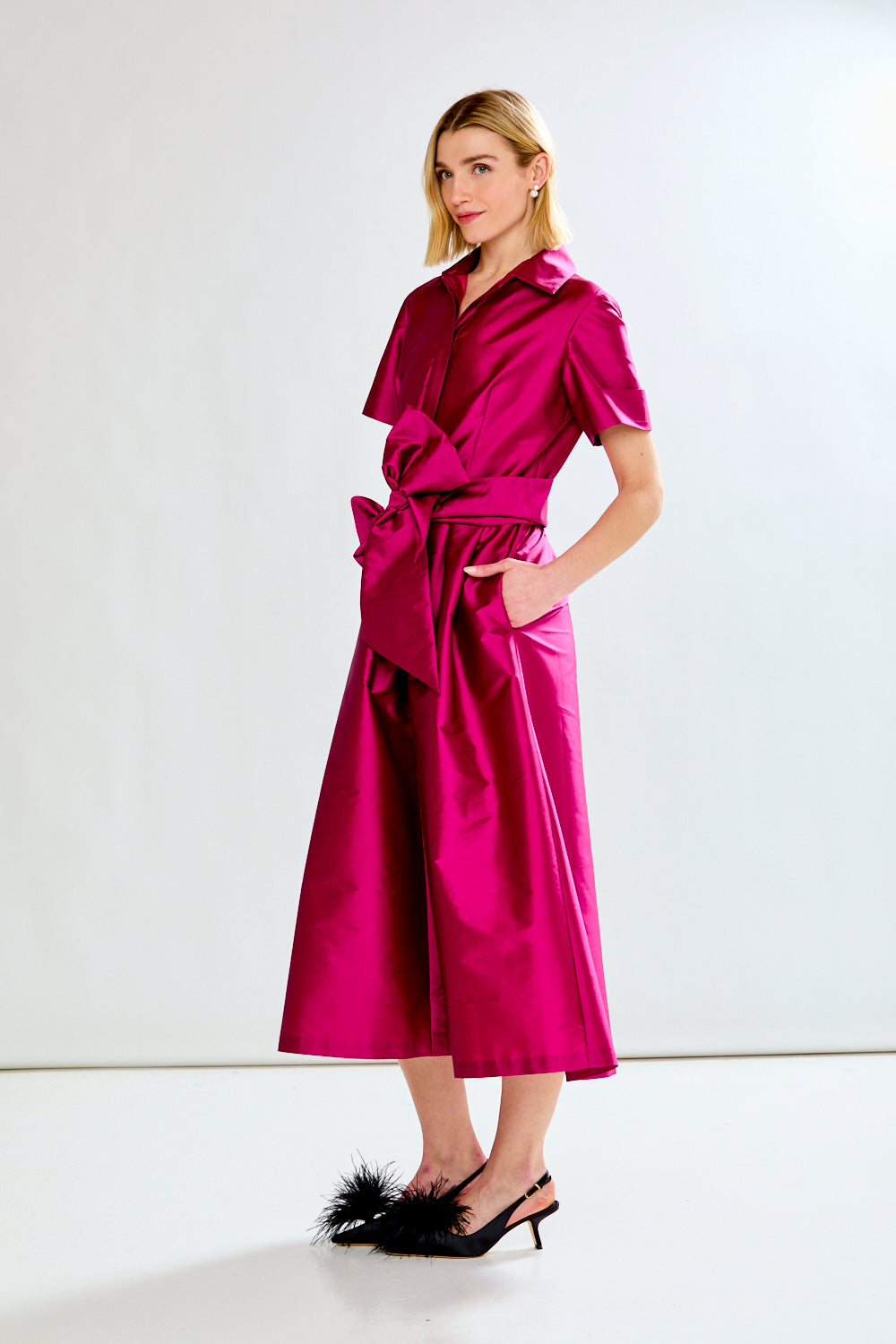 Woman wearing a bright pink dress with a white background