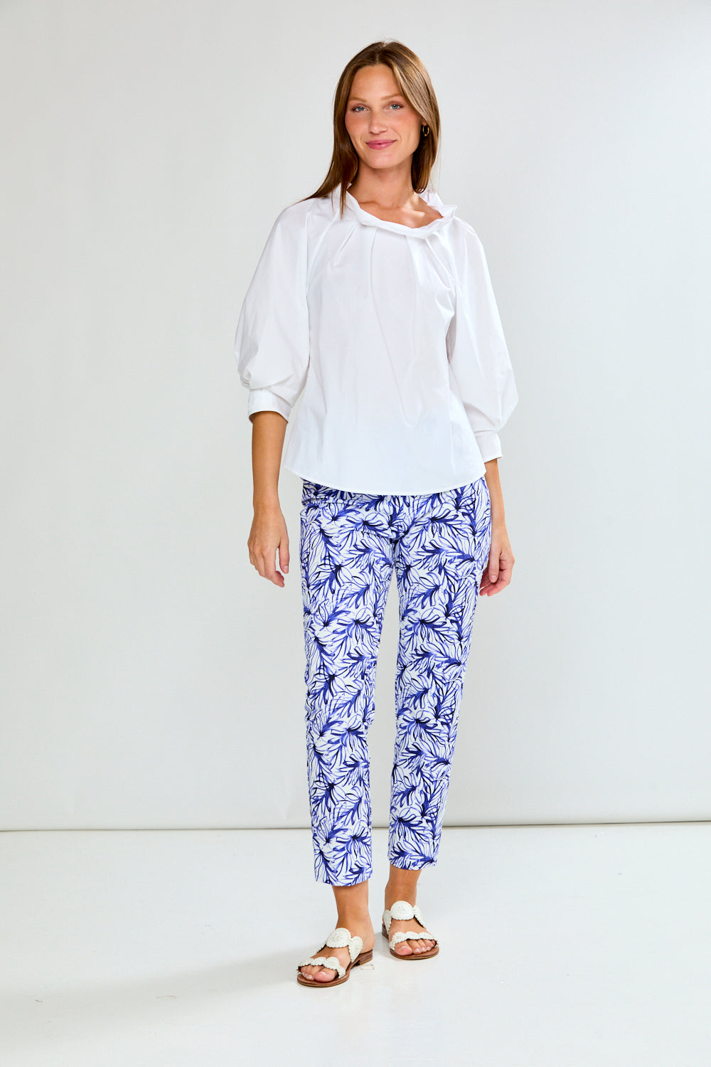 Woman wearing a white blouse and blue patterned pants on a white background