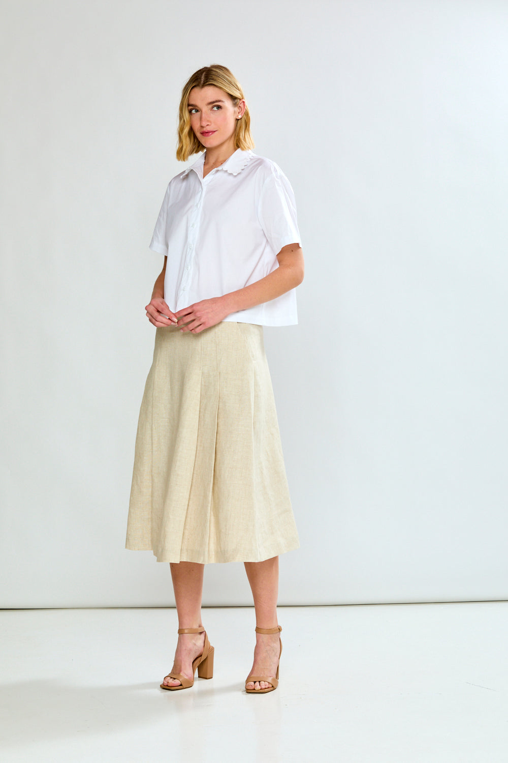 Woman wearing a white shirt and beige skirt on a white background
