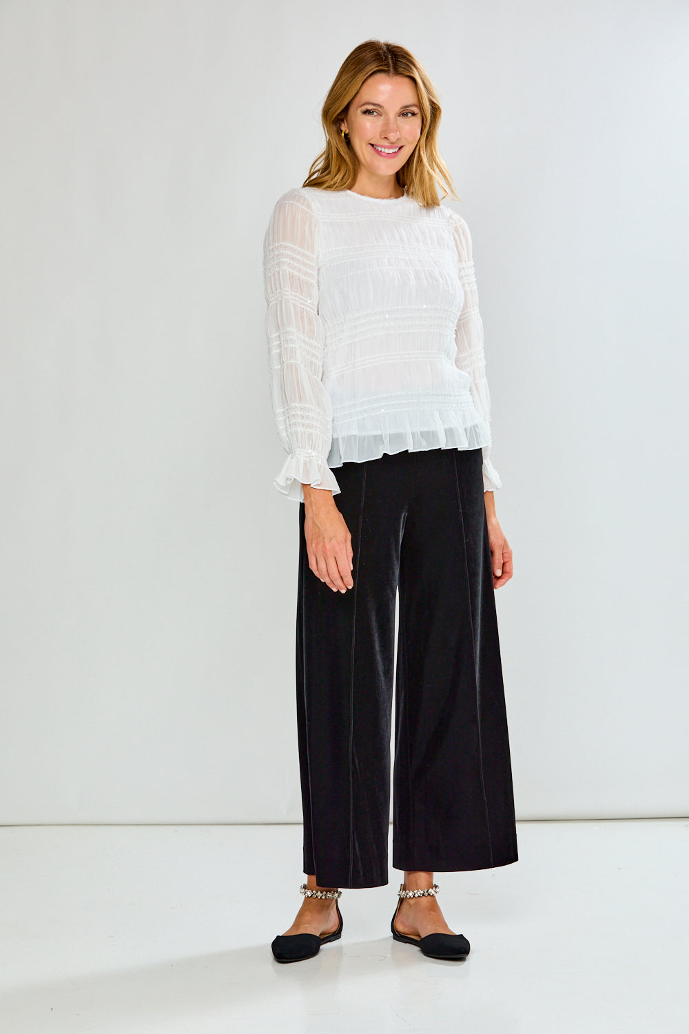 Woman wearing a white blouse and black pants on a white background