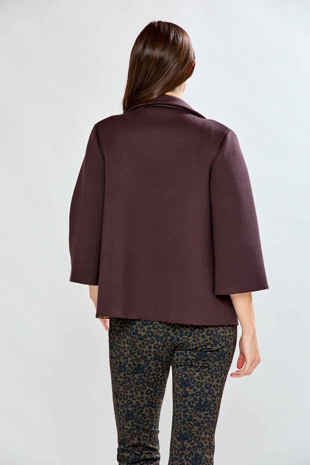 Person wearing a dark purple jacket and patterned pants on a white background